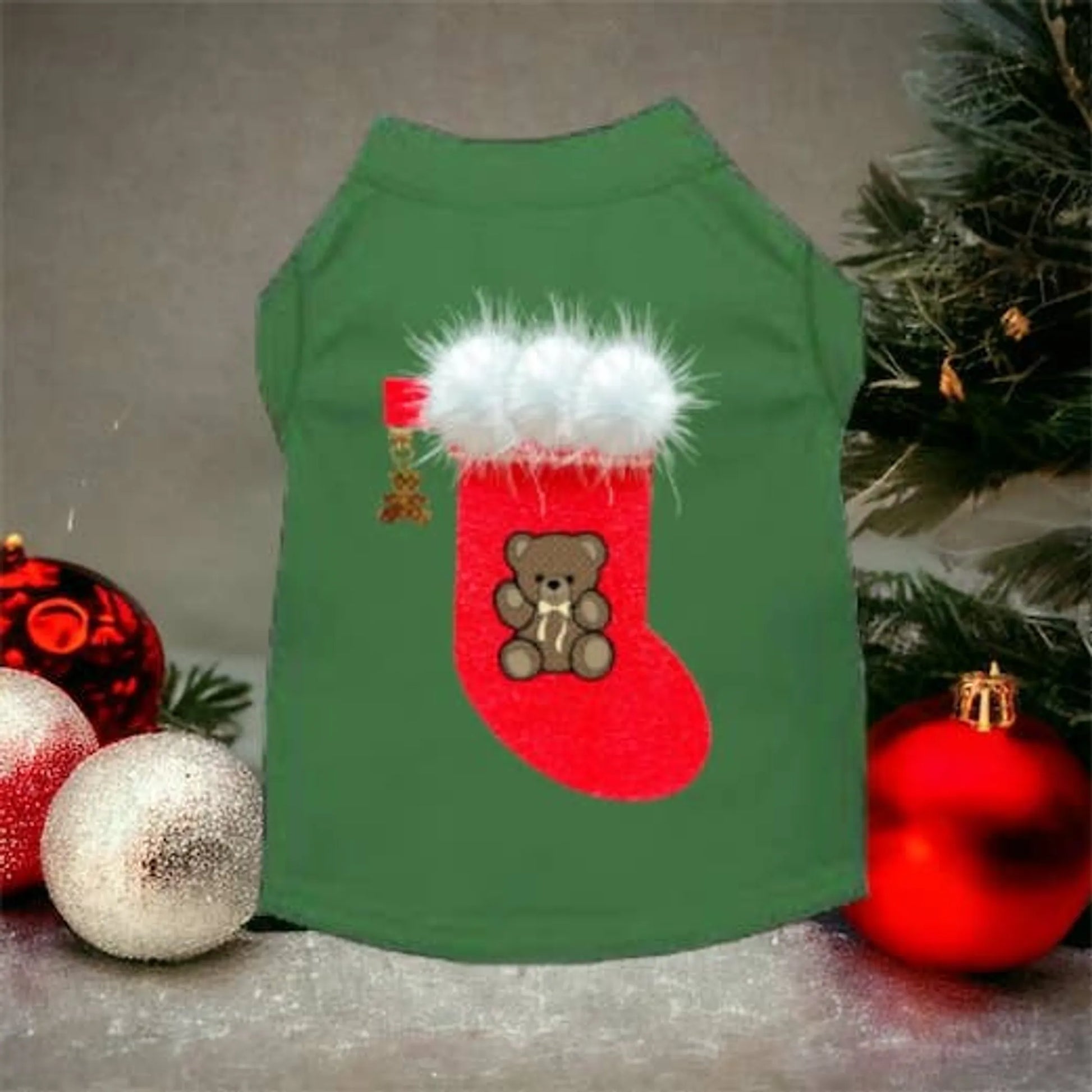 Green dog shirt with a Christmas stocking design featuring a teddy bear, surrounded by festive ornaments and a tree.