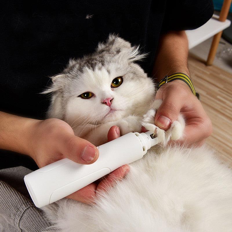 White and grey cat on back getting nails clipped with electric clippers