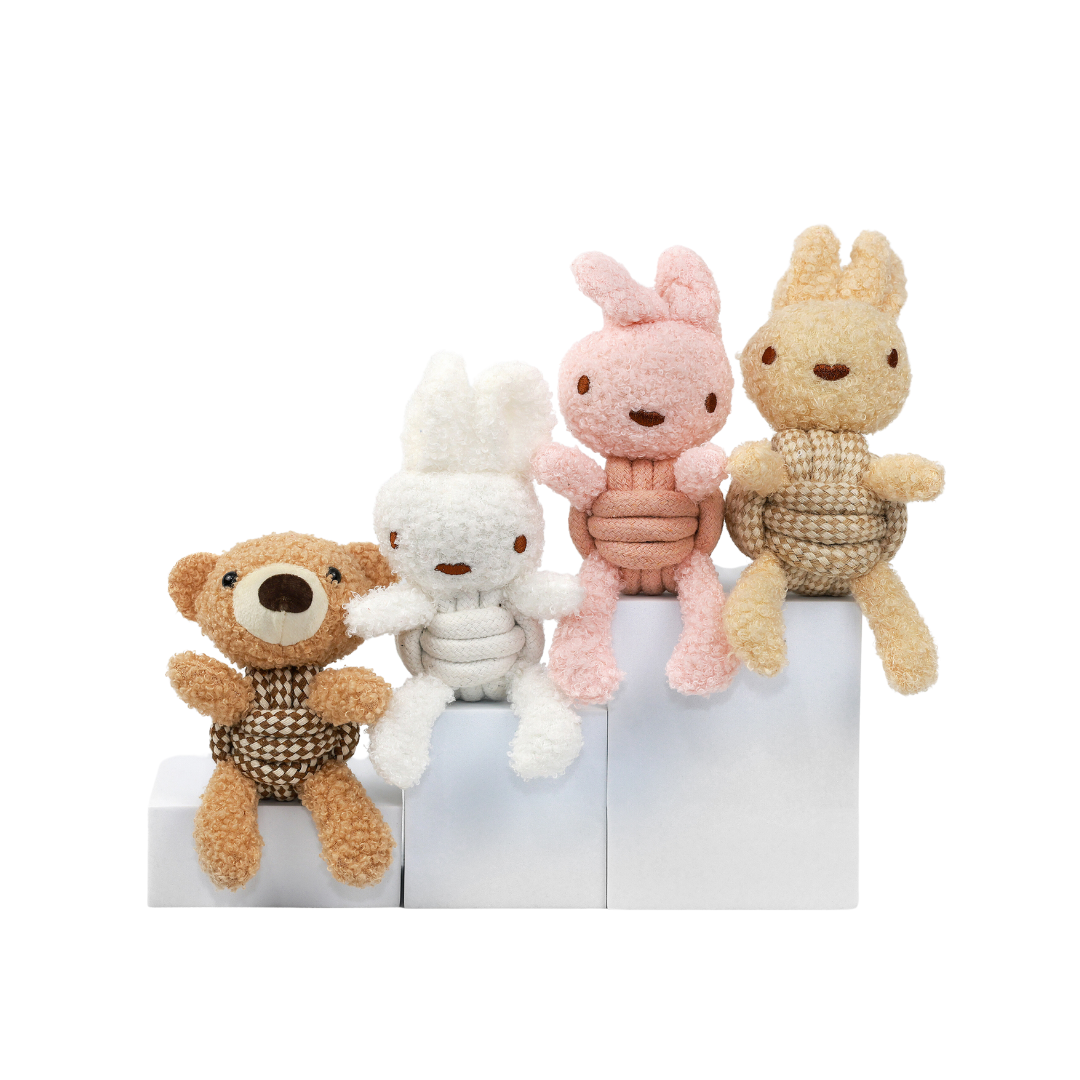 Four small plush toys, including a bear, rabbit, and two others, on a white surface with a white background.